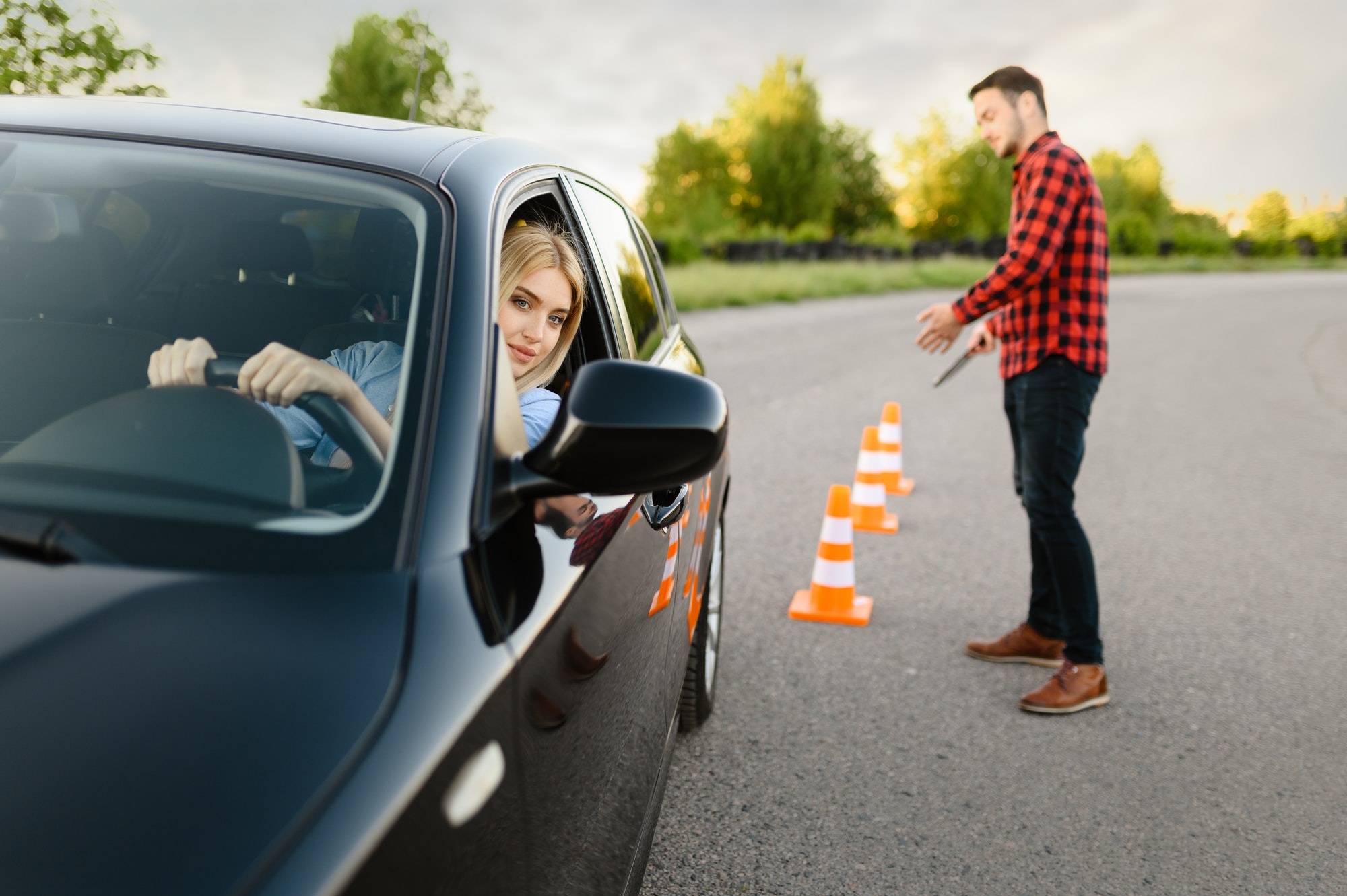 June Frau sitzt in einem schwarzen Auto und absolviert ein Fahrsicherheitstraining.